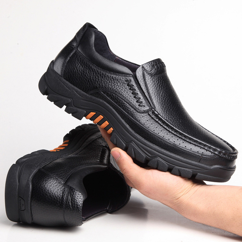 Photo d'une paire de chaussure orthopédique en cuir pour homme style mocassin dont une chaussure est tenue dans une main.