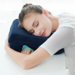 Femme dormant avec un oreiller bleu sous sa tête avec les bras croisés en dessous
