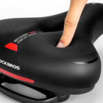 Selle de vélo noire avec doigt appuyant dessus.