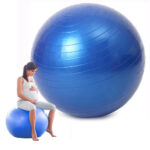 On voit un siège ballon ergonomique bleu et une femme enceinte assise dessus.
