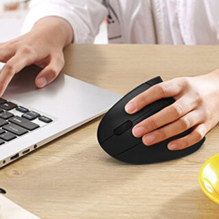 Personne à un bureau avec une main sur la souris ergonomique noire et l'autre sur son ordinateur portable