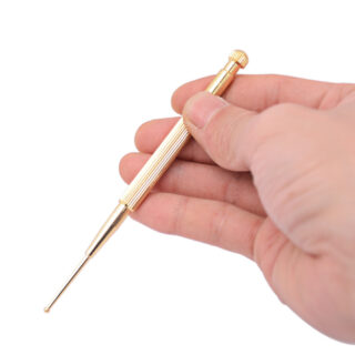 Stylo d'acupuncture doré tenu par quelqu'un sur fond blanc.