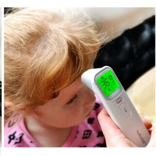 petite fille blonde se faisant prendre la température de son front avec un thermomètre numérique blanc avec écran LCD vert