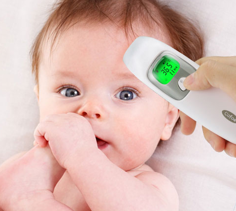 Photo d'un thermomètre numérique à infrarouge prenant la température sur la tête d'un bébé