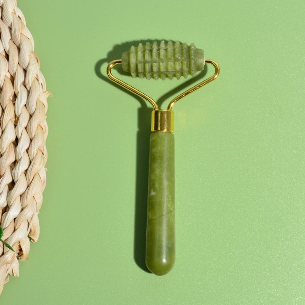 Photo représentant le rouleau de massage à micro aiguilles en pierre de jade sur un fond vert
