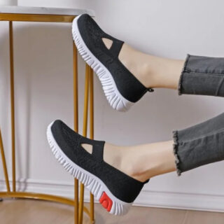 Chaussures noires avec semelle blanche portées par une femme dont on voit seulement les pieds.