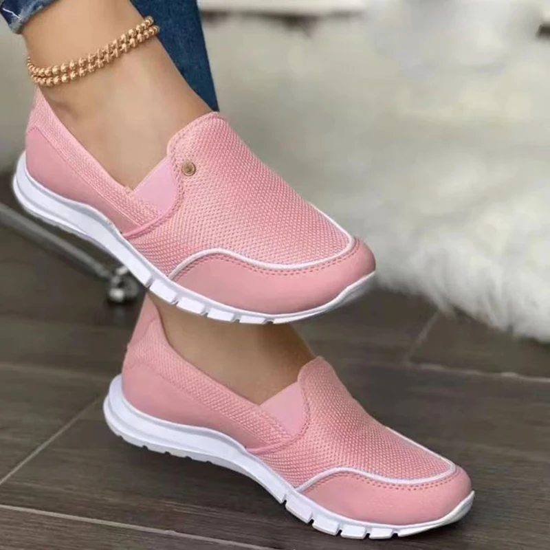 Chaussures orthopédiques roses vues sur des pieds d'une personne.