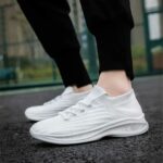 Chaussures orthopédiques de sport toutes blanches, portées par une mannequin sur un sol en goudron. On ne voit que ses pieds.