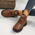 Paire de chaussures bottines orthopédiques marrons, à lacets, portées par une mannequin, on ne voit que ses pieds et ses chevilles.