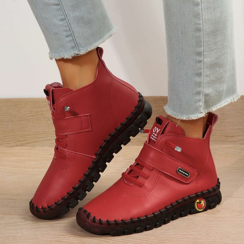 Paire de chaussures bottines orthopédiques rouges, à lacets, portées par une mannequin, on ne voit que ses pieds et ses chevilles.