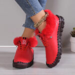 Paire de chaussures en cuir synthétique rouge, orthopédiques, style baskets, doublées à l'intérieur en fourrure synthétique. Portée par une mannequin, on ne voit que ses pieds.