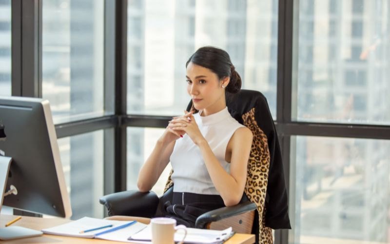 Femme assise sur une chaise ergonomique devant son bureau.
